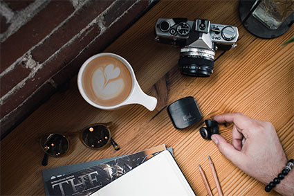 Klipsch T5 II True Wireless In-Ear Headphones on a desk with a cup of coffee and camera