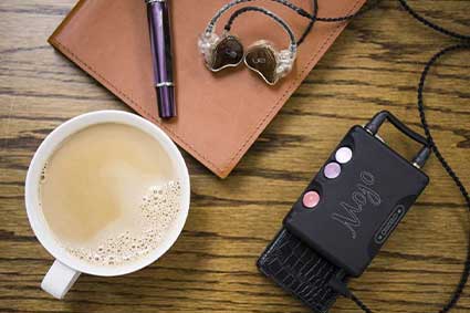 Chord mojo on a table next to a cup of coffee and a pair of IEMs