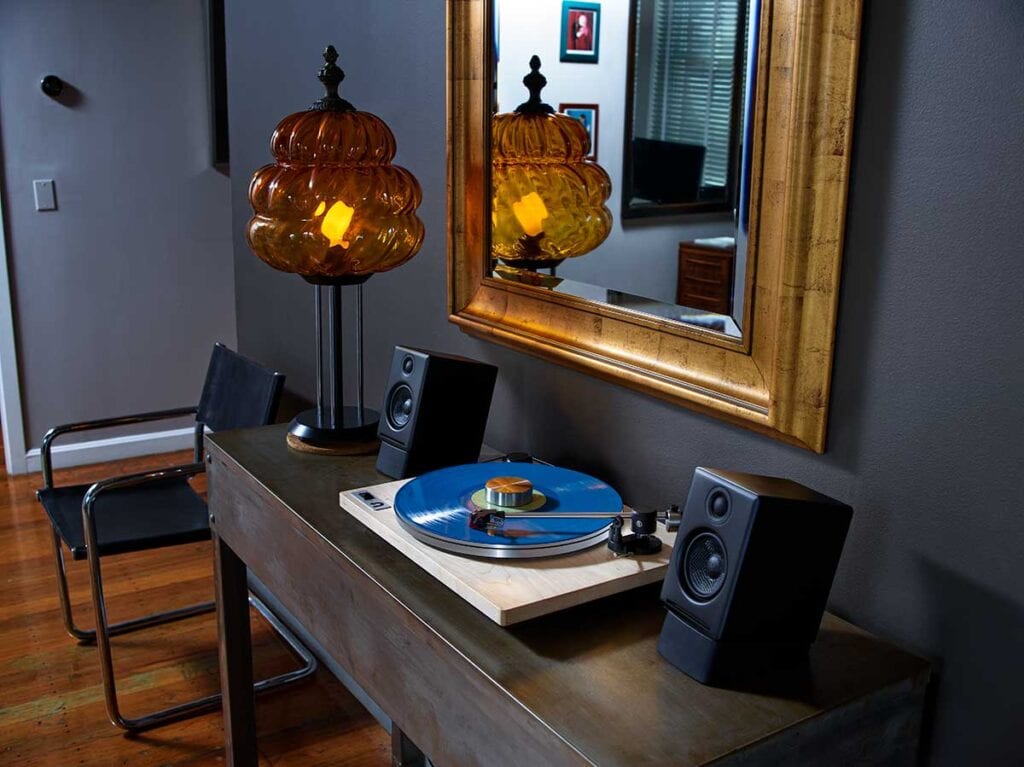 Turntable next to computer speakers on a wooden console table