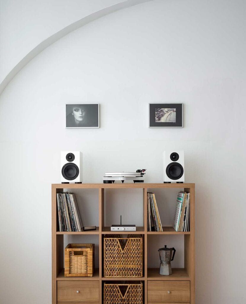 Pro-Ject white turntable and small speakers on top of a modular shelf