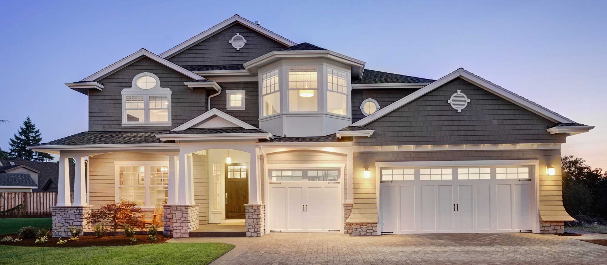 Modern gray sided home with white trim and all the lights turned on