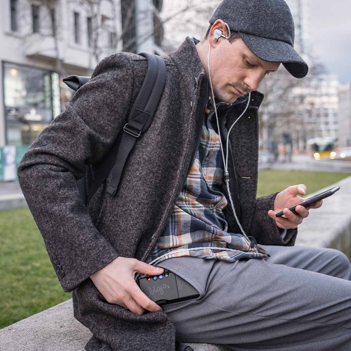 Chord Mojo 2 connected to computer and in-ear headphones sitting on desk