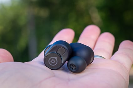 Devialet Gemini II Earbuds in Matte Black rest on the palm of a hand