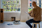 Man sitting on a stool with a Michell Gyro SE Turntable in the silver in the background