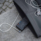 Chord Mojo 2 connected to in-ear headphones sitting on outdoor table