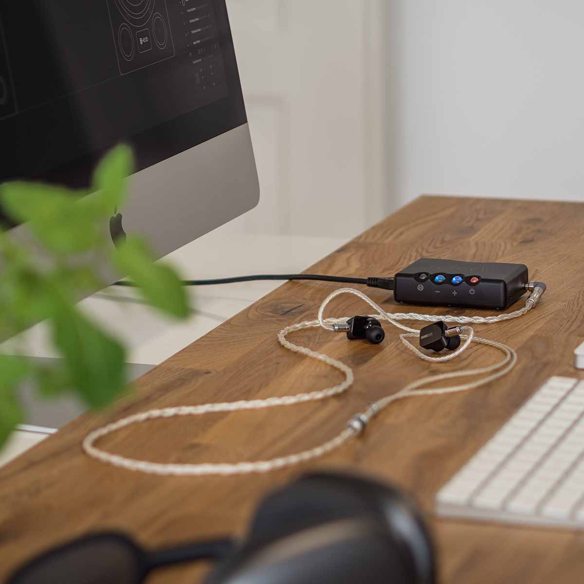 Chord Mojo 2 connected to  tablet and in-ear headphones sitting on desk