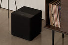 KEF Kube MIE Subwoofer on the floor beside a cabinet