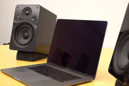 Peachtree M24 Powered Speakers in black set up with a Macbook Pro