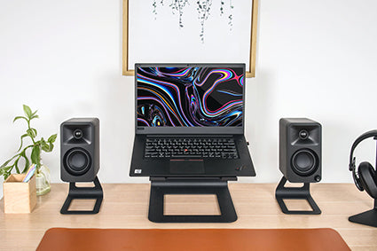 Kanto ORA Desktop Speakers on stands on either side of a laptop computer