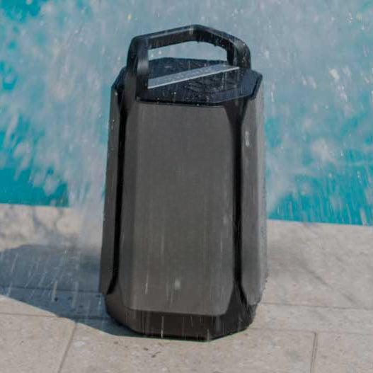 Portable Bluetooth speaker on a pool deck being splashed with water