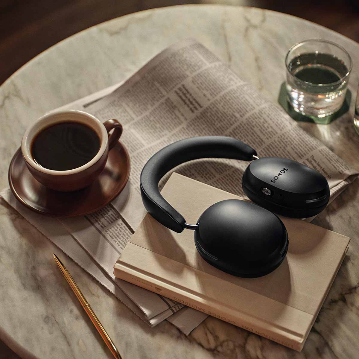 Sonos Ace Bluetooth Headphones w/ Active Noise Cancellation black on table with coffee and newspaper